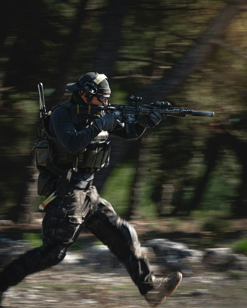 A shooter moving at speed with a scoped rifle shouldered